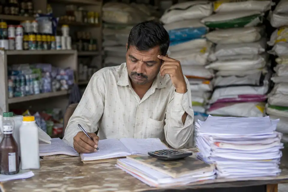 A Animal Feed & Veterinary channel partner working out incentives by hand with paper circulars and registers