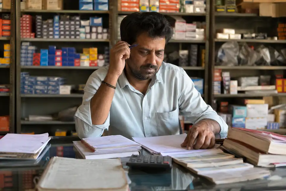 A Automotive Parts channel partner working out incentives by hand with paper circulars and registers