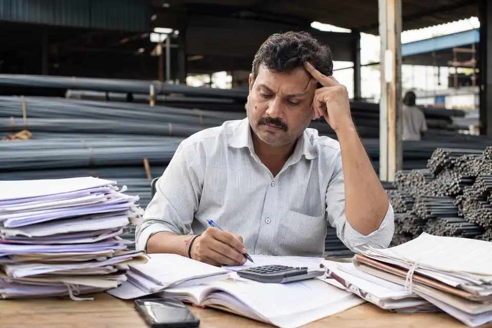 A TMT Steel channel partner working out incentives by hand with paper circulars and registers