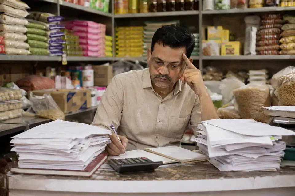 A FMCG channel partner working out incentives by hand with paper circulars and registers